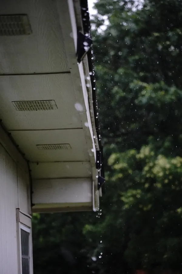 The underside of an eave and soffit with water running off the edge.