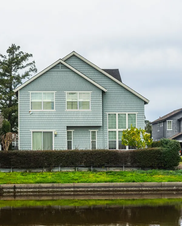A pale blue two-storey home with white trim, gutters running along the eaves.