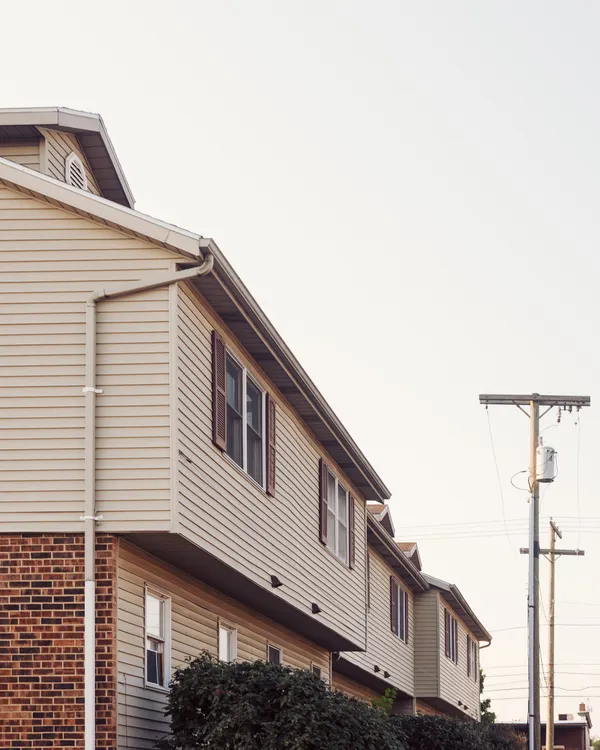 A row of two-storey homes with siding and brick, gutters and downspouts running down the ends.