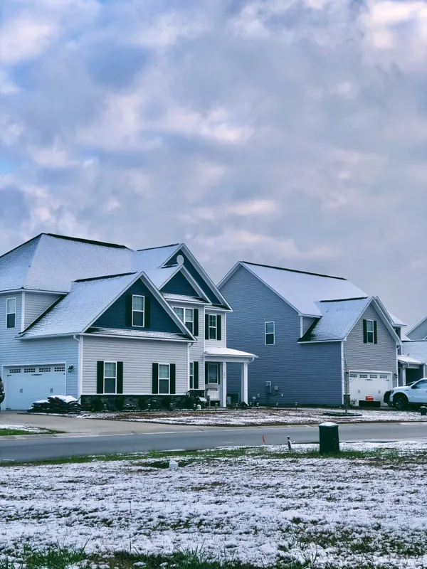 Snow lying on the roofs of a row of suburban homes.